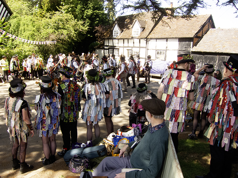 general view of the dance area with lots of border morris dancers wearing their colourful tatter jackets
