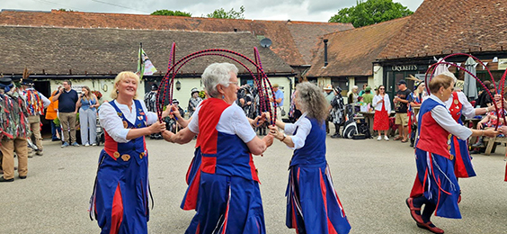 Nancy Butterfly dancing in the centre of the open space of Tardibigge Court with other sides watching on fom the edgees.