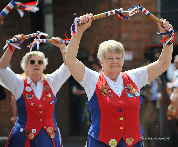 2 Nancy Butterfly Dancers with their decorated sticks raised above their heads