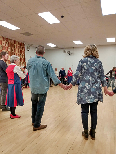 morris and folk dancers in a large circle prior to learning a folk dance
