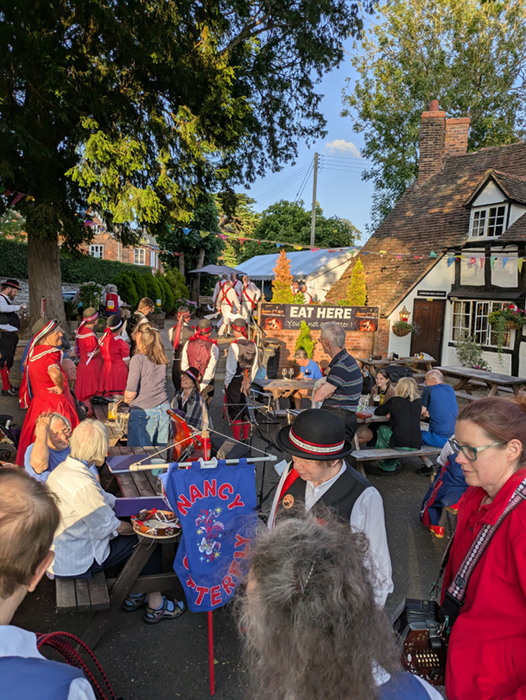 View of the busy garden of the Old Bull with hosts White Hart dancing in the background
