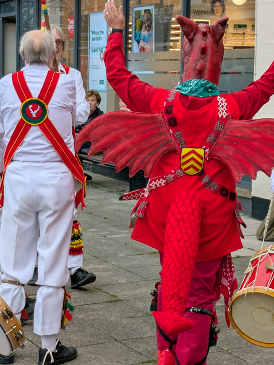 Looking from behind  at a White Hart dancer and the Cardiff 'Dragon' dancing side by side in Alcester.