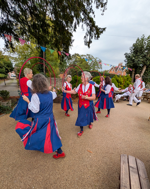 Nancy Butterfly in their red and blue kit performing a dance using red and blue decorated hoops