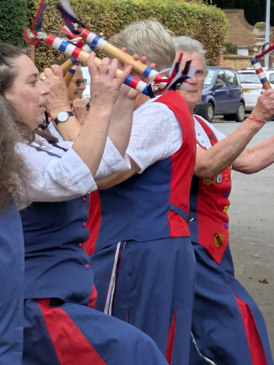 Close up view of 4 Nancy Butterfly dancers with their red white and blue decorated sticks with ribbons and bells.
